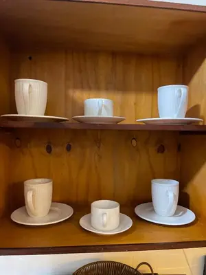 a shelf with white cups and saucers on them at Beautifull and Luxe Apartment 10 mn to the Int Airport in Los Paredones