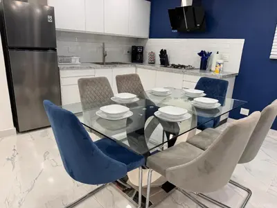 a kitchen with a glass table with chairs and a refrigerator at Blue Oasis Luxury in Sosúa