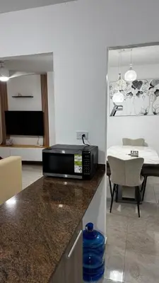 a kitchen with a microwave on a counter with a living room at New and Comfortable Apartment in Ciudad Juan Bosch in San Isidro