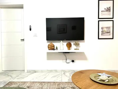 a living room with a tv on a white wall at New Jacuzzi Beach Fun 2 bedroom at Cana Rock Star in Punta Cana