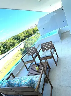 two chairs and a table on a balcony with a pool at New Jacuzzi Beach Fun 2 bedroom at Cana Rock Star in Punta Cana