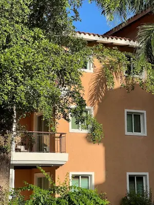 an orange building with a balcony and trees at Cozy 3 Bedroom Apartment with Pool & Private Beach in Bávaro Punta Cana in Punta Cana