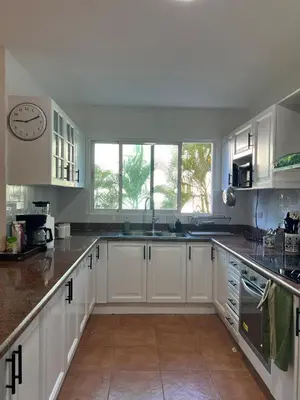 a kitchen with white cabinets and a clock on the wall at Cozy 3 Bedroom Apartment with Pool & Private Beach in Bávaro Punta Cana in Punta Cana