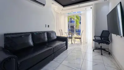 a living room with a black couch and a television at One Bedroom Apartment - Wi-Fi - BBQ in Sosúa