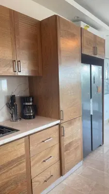 a kitchen with wooden cabinets and a refrigerator at Luxurious 3-Bedroom Apartment in Juan Dolio with Pool Access in Juan Dolio