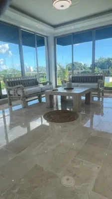a living room with a table and benches and windows at Spacious 3-Bedroom Apartment with Pool Access in Juan Dolio in Juan Dolio
