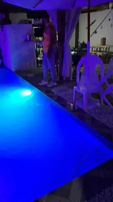 a little girl standing next to a pool with purple lights at Villa Manuel Rodriguez