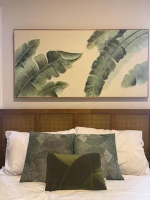 a painting above a bed with green pillows at Garden Breeze Pool & Beach Escape l Bali 102 in La Laguna
