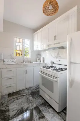 a white kitchen with a stove and a refrigerator at Oz Residence Beach Two-Bedroom Apartment & Free Parking