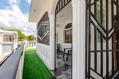 a white house with a balcony with green grass at Oz Residence Beach Two-Bedroom Apartment & Free Parking