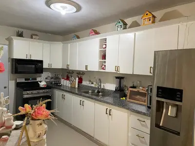 a kitchen with white cabinets and a stainless steel refrigerator at My Little House in Constanza
