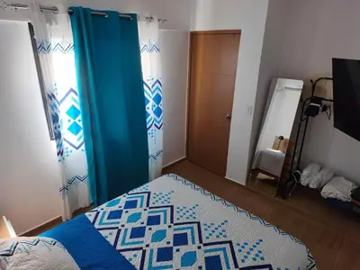 a bedroom with a bed and a blue curtain at Brisa del Mar Punta Cana Apartment in Punta Cana