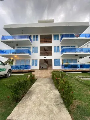 a white building with blue windows and a driveway at Departamento en la playa de palenque in Sabana Grande de Palenque