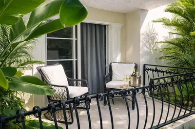 a balcony with two chairs and a table with wine bottles at Escapada Perfecta Piscina 5 Min a la Playa in Punta Cana