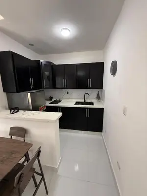 a kitchen with black cabinets and a sink and a table at Moon Apartamentos D3 in San Cristóbal
