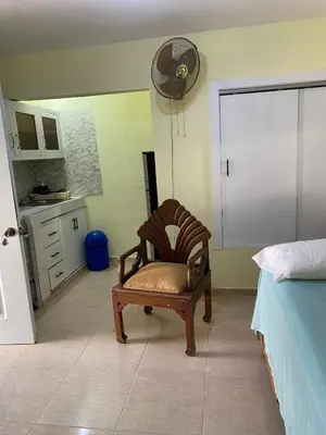 a bedroom with a chair and a kitchen with a fan at Nido del patio, 40 min to Bocachica beach 5 center in La Piedra