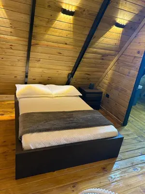 a bed in a room with a wooden wall at Cabaña Silencio Verde in Jarabacoa