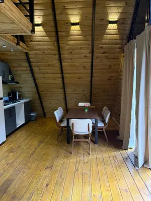 a wooden room with a table and chairs and a kitchen at Cabaña Silencio Verde in Jarabacoa