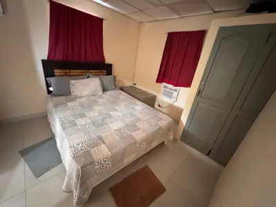 a bedroom with a bed with red curtains and a door at Casa de campo El Bonao in Higuey
