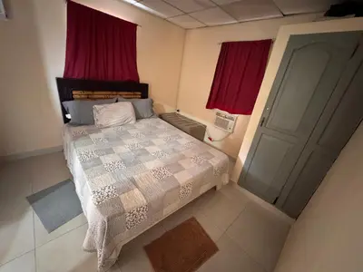 a bedroom with a bed with red curtains and a door at Casa de campo El Bonao in Higuey