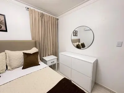 a white bedroom with a bed and a mirror at Cómodo y moderno apartamento en Santiago Gurabo Sin costo de limpieza in Santiago de los Caballeros