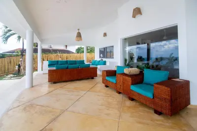 a patio with wicker furniture and blue chairs at Villa Bella Vista - Luxury Ocean View and Private Pool, Las Terrenas in Las Terrenas