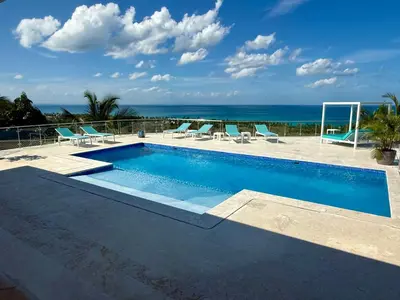 a swimming pool with chairs and the ocean in the background at Villa Bella Vista - Luxury Ocean View and Private Pool, Las Terrenas in Las Terrenas