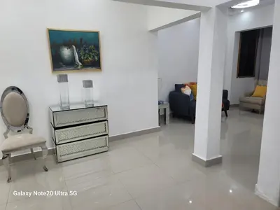 a white living room with a chair and a dresser at Colonial suites in Santo Domingo