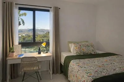 a bedroom with a bed and a desk with a window at Mountain and pool modern apartment in Santiago de los Caballeros
