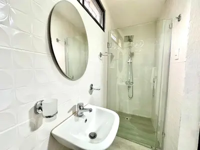 a white bathroom with a sink and a shower at Padres Las Casa in Santiago de los Caballeros