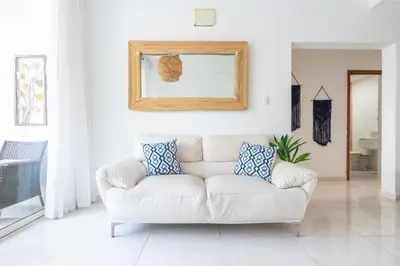 a white living room with a white couch and a mirror at Coastal Corner -Beach-Pool-Terrace-Parking-Pets in Villas del Mar