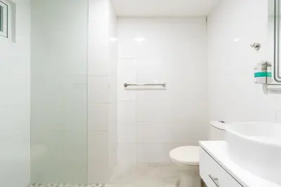 a white bathroom with a toilet and a sink at Coastal Corner -Beach-Pool-Terrace-Parking-Pets in Villas del Mar