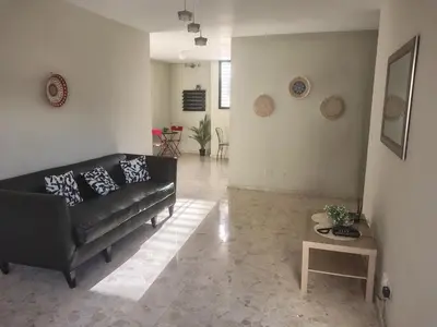 a living room with a black couch and a table at Comfortable and quiet single room in Santo Domingo