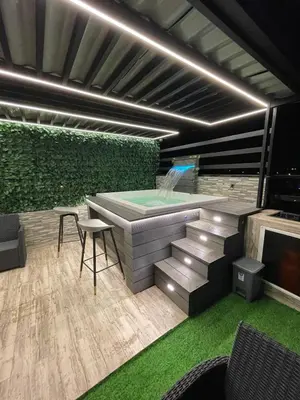 a patio with a jacuzzi tub and a green wall at Luxury apartment private rooftop & jacuzzi in Santo Domingo