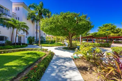 a walkway in front of a building with trees and plants at Iberostate 2BR Apartment - BBQ, Terrace, Lake & Golf Views, Beach Club Access in Punta Cana