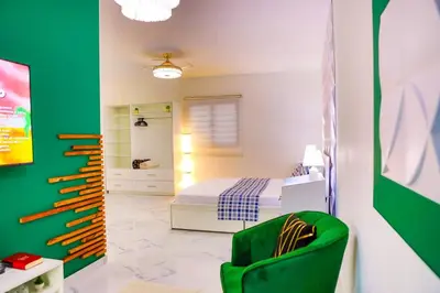 a bedroom with a bed and a green chair at Agapimou apartments H in Gaspar Hernández