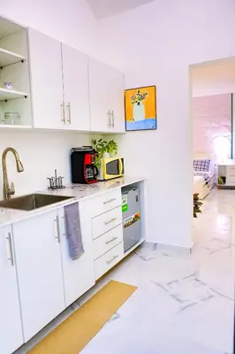a white kitchen with a sink and a microwave at Agapimou apartments H in Gaspar Hernández
