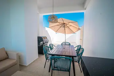a table with chairs and an umbrella in a room at Golf View Penthouse with Private Rooftop & BBQ in Punta Cana