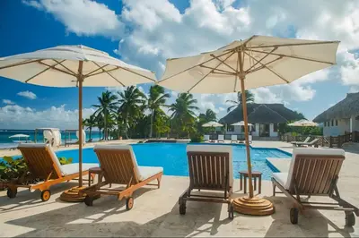 a group of chairs and umbrellas next to a pool at Golf View Penthouse with Private Rooftop & BBQ in Punta Cana