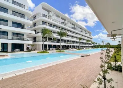 an external view of a large apartment building with a swimming pool at Golf View Penthouse with Private Rooftop & BBQ in Punta Cana