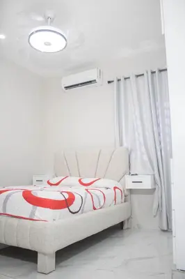 a white bedroom with a bed and a light at Apartamentos carrasco in Nagua