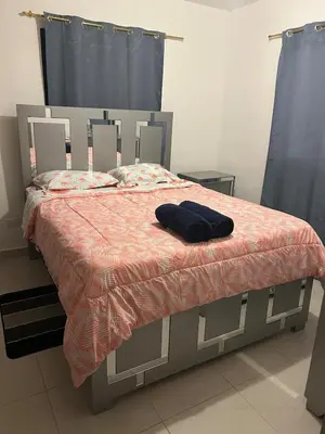 a bedroom with a bed with a orange comforter at Próximo al aeropuerto en santo domingo in La Javilla
