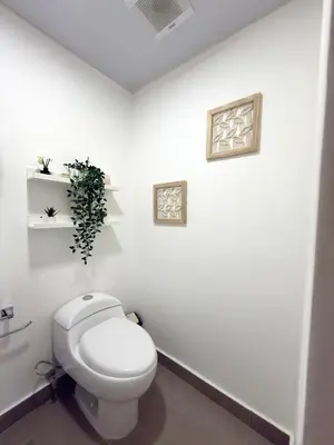 a bathroom with a toilet and a plant on the wall at Apartamento en livera RD in Santiago de los Caballeros