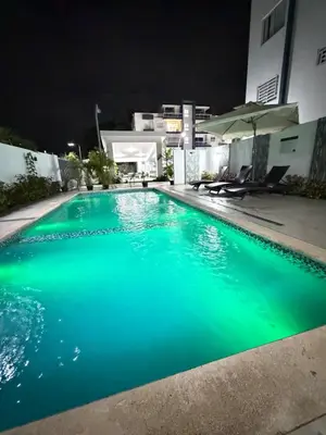 a swimming pool at night with green water at Piscina Playa 3 Min Aeropuerto Cerca in Boca Chica