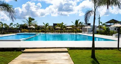 a swimming pool in a resort with palm trees at Villa Brisa Marina in Boca Chica