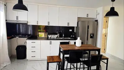 a kitchen with white cabinets and a table and chairs at Villa Brisa Marina in Boca Chica