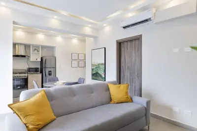 a living room with a gray couch and yellow pillows at Nestled Comfort in 1BR -WeHost DR in Santo Domingo
