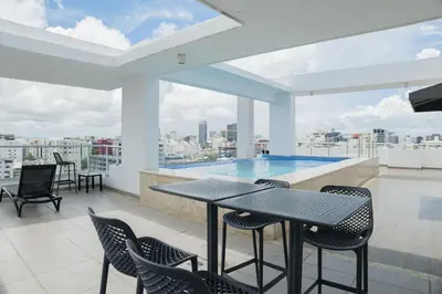 a balcony with a table and chairs and a swimming pool at Nestled Comfort in 1BR -WeHost DR in Santo Domingo