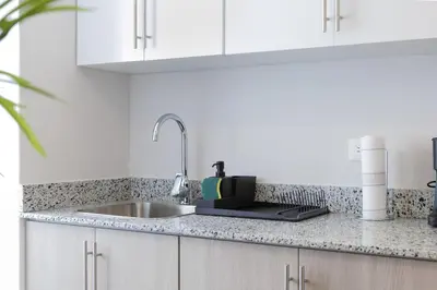 a kitchen with a sink and white cabinets and a counter top at Nestled Comfort in 1BR -WeHost DR in Santo Domingo