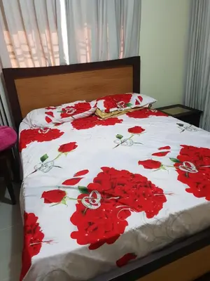 a bed with red flowers on a white comforter at My house 56 in San Francisco de Macorís